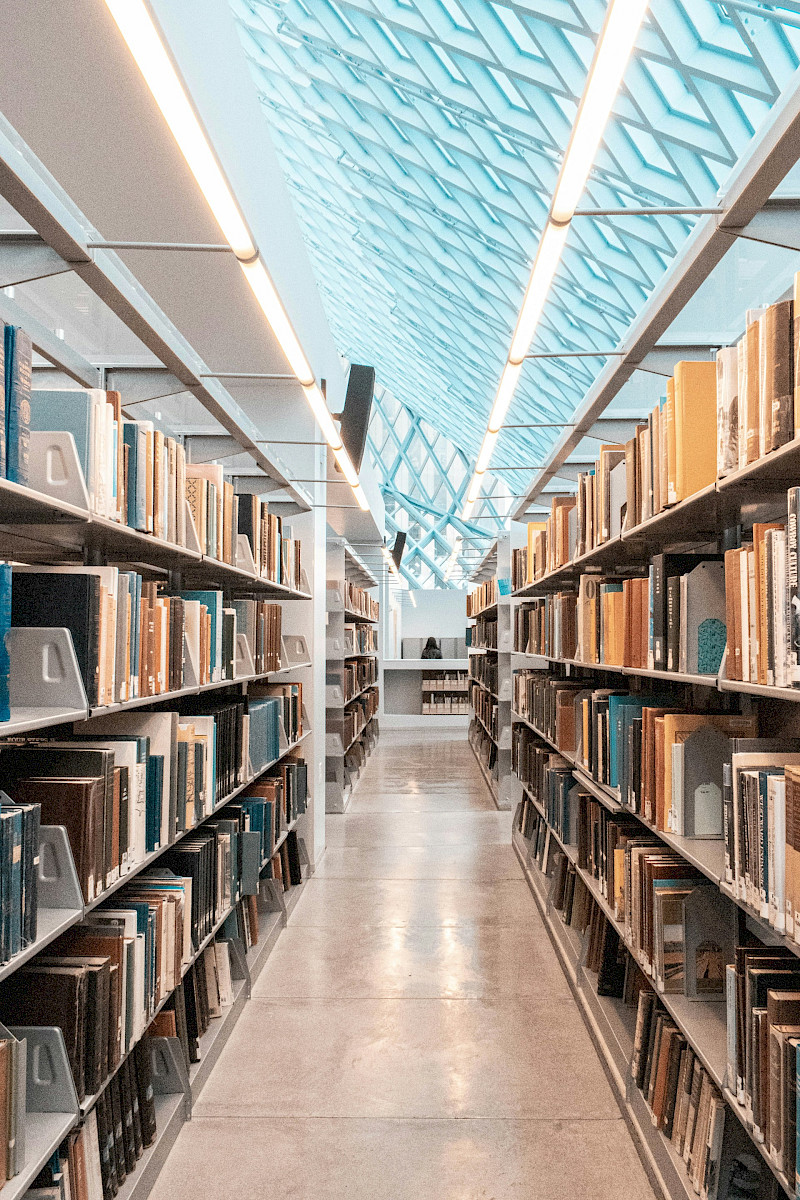 brown wooden book shelves in library. Photo by Shunya Koide, Unsplash.