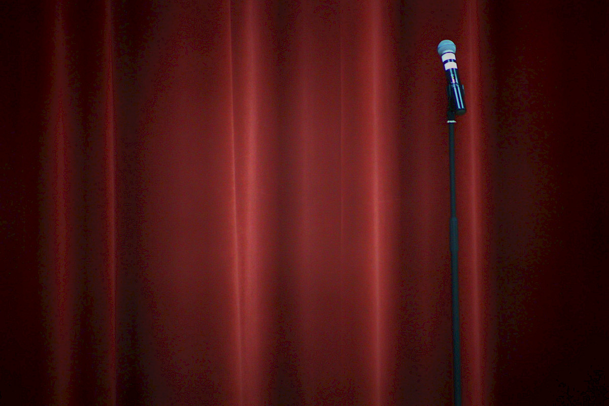 black microphone on red curtain. Photo by Joshua Hoehne, Unsplash.